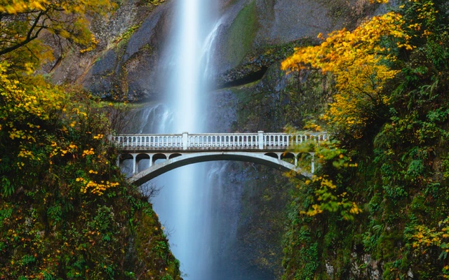 A bridge over a gorge with a waterfall in the background